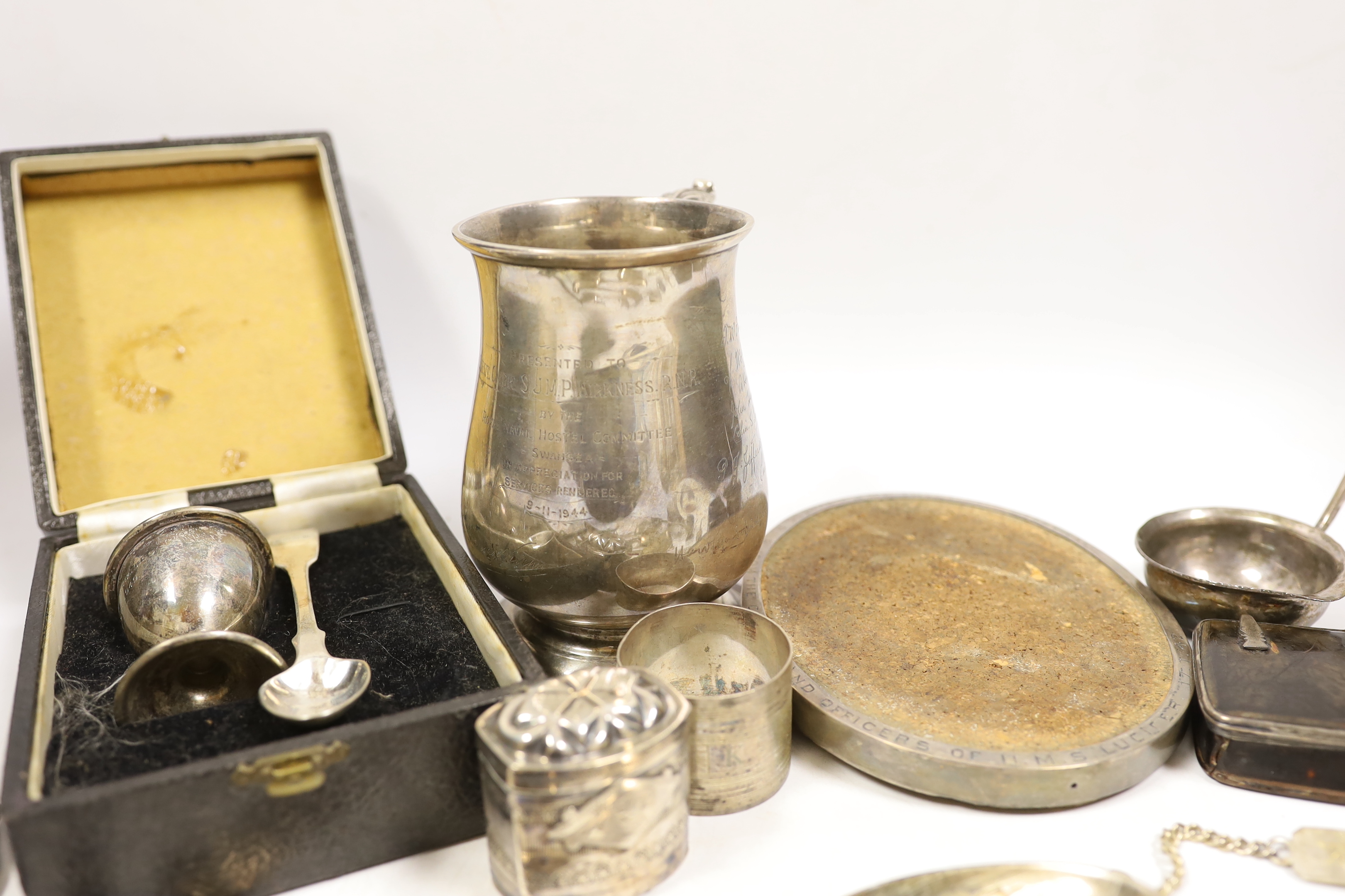 Assorted silver items including a silver mug engraved with signatures and inscription relating to Lieut. Commander S.J.M.P. Kirkness, R.N.R., London, 1942, 13cm, four 18th century base mark table spoons, a George IV cadd